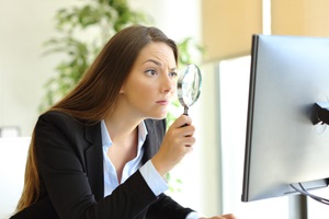 office worker checking online content on computer using a magnifying glass