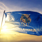 Oklahoma flag flying in front of the sunrise